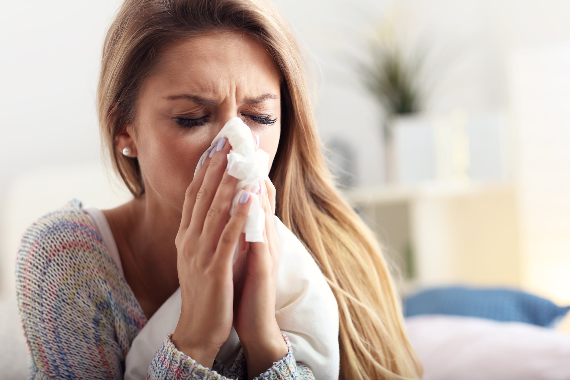 Sick woman at home wiping her runny nose